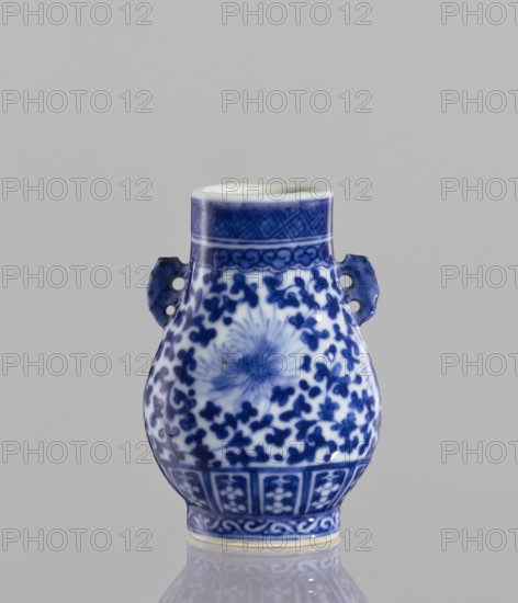 Hu-type vase, ceramics, flowers, hu vessel, blue and white porcelain, Chinese art, vases, Chinese culture, lotus tendril ornament, 17th century, China, vessel, height 10.5 cm, diameter 4 cm, A small ceramic vase with a bulbous body and narrow neck sits against a neutral gray background, predominantly white with deep cobalt blue painted decoration; the blue forms floral and abstract motifs covering the body, a radiating flower-like design visible on the front, and banded geometric patterns around the neck and base; there are a pair of small blue handles with cutout holes on opposite sides, and the vase has a glossy finish that creates subtle reflections on the surface.