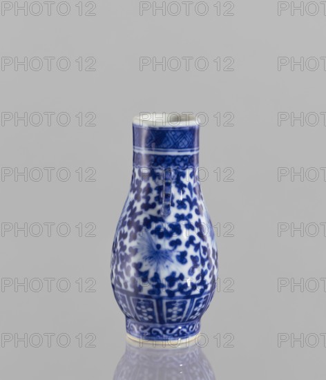 Hu-type vase, ceramics, blue and white porcelain, Chinese art, hu vessel, lotus tendril ornament, flowers, 17th century, China, vessel, height 10.5 cm, diameter 4 cm, A small ceramic vessel with a bulbous body and narrow neck sits against a plain light gray background, decorated in blue and white with intricate floral and geometric patterns; the neck has a band of darker blue with a subtle lattice motif, the body is covered in dense blue floral shapes with a central floral burst motif on the front, and a patterned border encircles the lower portion above a pale rim at the base, the surface is glossy and reflective showing soft highlights and a faint reflection of the vessel on the surface below.