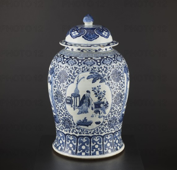 Pot with cover; maker, resource pots; blue-and-white porcelain; Chinese; plant motifs and mountain landscapes; decorative vessel; ceramics; Qing style; Qing dynasty 1644–1911; Ming 1368–1644; possibly 1st half of the 17th century; China; vessel; height 60 cm; diameter 36 cm, A ceramic lidded jar with a rounded body and flared base sits against a dark background; the jar is decorated in a blue-and-white palette with intricate floral and scrolling patterns covering most surfaces, a central medallion on the body containing a scene with a few human figures and furniture, and a domed lid topped by a rounded finial that shares the same blue-and-white decoration.