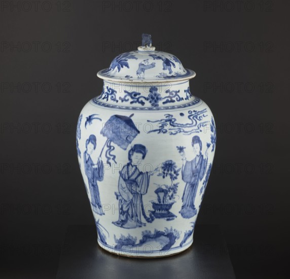 Pot with a cover, Chinese, Qing dynasty 1644–1911, 18th century. Blue-and-white porcelain storage vessel, decorative figurative scenes including images of birds; possibly a Japanese product exported to Europe imitating Chinese wares. Height 58.5 cm, diameter 37 cm., A ceramic lidded jar with blue painted decoration on a white background sits against a dark gray backdrop; the jar has a rounded body tapering toward a narrower base and a flared rim under a domed lid topped with a small sculpted finial. The surface shows several painted figure scenes in cobalt blue depicting standing human figures in flowing robes, a person holding an umbrella-like object, floral and plant motifs, stylized cloud or wave forms, and decorative scrollwork near the neck. The visible colors are blue, white, and the dark gray of the background, with a small band of natural clay color at the jar’s base.