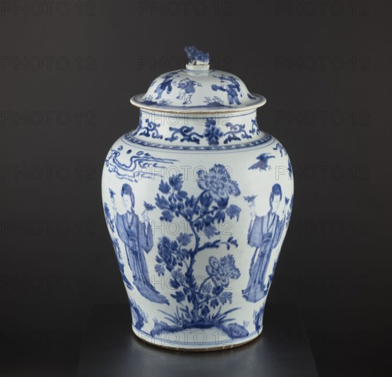 Pot with a cover, Chinese, Qing dynasty 1644–1911, 18th century. Blue-and-white porcelain storage vessel decorated with figurative scenes and images of birds; possibly a Japanese product exported to Europe imitating Chinese wares. Height 58.5 cm; diameter 37 cm., A porcelain lidded jar shown against a dark background with a smooth white surface painted in blue. The jar has a rounded body tapering toward the base and a domed lid topped with a small sculpted figure. Blue painted floral branches and large blossoms decorate the central area, flanked by a group of standing human figures on each side wearing long robes. Decorative blue cloudlike and scroll motifs encircle the neck and shoulder, and a narrow band of patterned decoration runs near the rim. A small bird is visible in blue on the upper body, and the lid features additional blue-painted scenes and motifs. The visible colors are white and shades of blue set against a dark gray background.