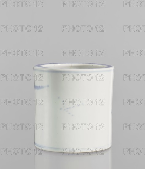Brush vessel, ceramics, blue and white porcelain, Chinese art, landscape motifs, Chinese culture, 18th century China, vessel, height 12.8 cm, diameter 12.7 cm., The image shows a cylindrical ceramic cup with a smooth glossy surface, primarily white with subtle pale blue accents along the rim and base and faint blue speckled marks on the body; the cup is set against a neutral light gray background and rests on a reflective surface that creates a soft mirror of its base.