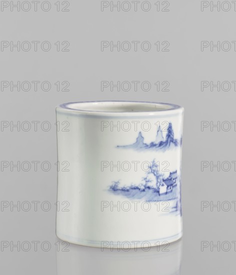 Brush vessel, 18th century, China; ceramics, blue and white porcelain; height 12.8 cm, diameter 12.7 cm; decorated with landscape motifs., A cylindrical ceramic vessel with a glossy white surface and delicate pale blue painted decoration, showing a small landscape scene with stylized mountains, trees, and a pavilion in blue tones; the rim and base have thin blue bands, and the object sits on a reflective light-gray surface against a soft gray background.