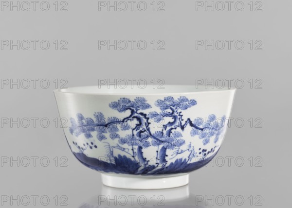Bowl, ceramics, blue and white porcelain, inscriptions, landscape motifs, fishermen; Chinese, Qing 1644–1911, 19th century, South China; vessel, height 8.8 cm, diameter 17 cm. Inscriptions: ?? Wèi Shui, the Wei River, ??? tóu gan rì, the day of casting the fishing rod, ?? Qí Shan, Mount Qi, ??? rù mèng chén, entering a dream in the morning — verse evoking a peaceful or nostalgic scene of fishing by the Wei River and Mount Qi., A white ceramic bowl with a glossy surface sits against a gray background, decorated around its exterior with a blue painted landscape motif showing stylized trees with textured foliage, winding branches, and ground vegetation, with darker blue shading along the lower rim and a white foot at the base.