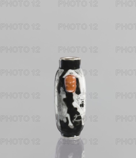 Flask - snuffbox, Chinese, ceramics; figurative genre scenes of horses and riders; Qing dynasty, Qianlong period 1736–1795, 18th century; vessel; height 6.4 cm., A small elongated cylindrical object sits upright against a light gray background, showing a glossy surface with predominant colors of black, white, and a distinct orange-brown raised oval element on its front; the object has painted or etched white illustrations on the black areas and a reflective sheen at its base.