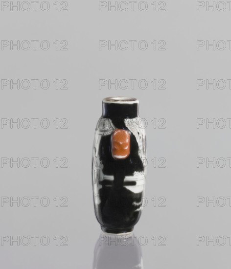 Flask - snuffbox, Chinese, ceramics; flask with figurative genre scenes of horses and riders; Qing dynasty, Qianlong period 1736–1795, 18th century; vessel; height 6.4 cm., A small cylindrical object stands upright on a reflective surface against a pale gray background, primarily showing black and white decoration with a prominent glossy reddish-brown protrusion on one side; the object has a rounded top with a thin lighter rim and areas of intricate white patterns and shapes on the black body, with subtle highlights and reflections on its glossy surface and a faint mirrored image below it.