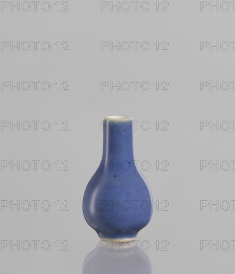 Bottle, Chinese culture, Chinese ceramics, poudre bleu, 19th century, China, vessel, height 5.3 cm, A small rounded ceramic bottle with a narrow cylindrical neck, glazed in a smooth blue that shows subtle variations in tone and a few tiny darker specks, standing on a reflective surface; the rim and base edges show slight off-white and beige hues, and the background is a plain light gray.