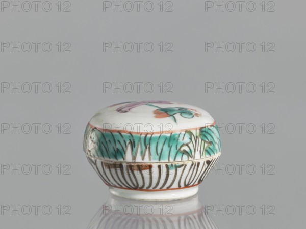 Box with a lid, Chinese, colored porcelain with figural scenes, 19th century, China, vessel, height 4.6 cm, width 6.9 cm, A small round ceramic box with a domed lid sits on a reflective surface against a plain gray background; the box is primarily white with painted decorations including a band of teal green foliage around the upper side, thin brownish-orange outlines, and dark brown linear patterns on the lower section, while the top shows touches of teal green and muted pink on a white field.