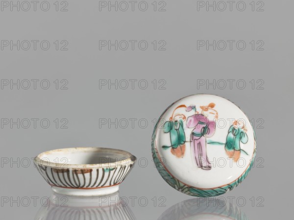 Box with a lid, Chinese, figural scenes, colored porcelain, boxes, gift, 19th century, China, vessel, height 4.6 cm, width 6.9 cm, A small round porcelain dish and its lid sit on a reflective surface against a gray background; the dish is white with a patterned exterior showing dark curved lines and a thin band of orange near the base, while the lid is white with a painted scene in pastel colors depicting a central standing figure in pink and purple flanked by two smaller figures in green and orange, and the lid rim features a green leafy border.