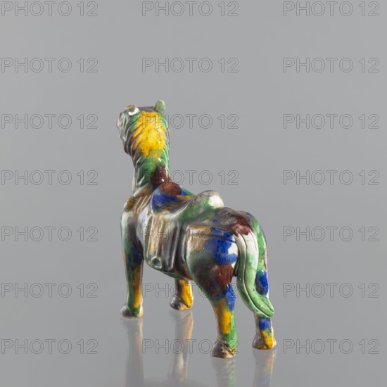Mule, Chinese, Qing dynasty 1644–1911, 18th century; colored porcelain animal figurine mule; sculpture; height 19.1 cm, width 19.4 cm., A small glazed ceramic horse figurine viewed from behind and slightly to one side, showing a rounded body, four legs, and a short tail; the surface displays a mottled mix of green, blue, yellow, brown, and white glazes with glossy reflections, and the figure stands on a smooth gray background that reflects a faint mirrored image of the horse.