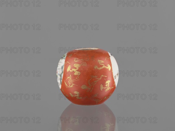 Vase, Chinese, Qing dynasty 1644–1911, early 19th century. Porcelain vessel jug with birds, female figures, and landscape motifs. Height 7.4 cm; diameter 8.6 cm., A round ceramic vessel with a glossy red-orange central band decorated with gold-painted bird and cloud motifs, flanked by white side panels that show portions of painted scenes in muted colors, all set against a solid gray background with a faint reflective surface beneath that mirrors the vessel's colors.