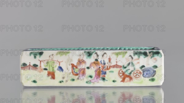 Cricket Cage, Chinese, Qing dynasty 1644–1911, colored porcelain vessel depicting animals engaged in fighting cricket fighting, 1st half of the 19th century, height 17.9 cm, width 4.6 cm., A rectangular porcelain tray with rounded corners sits against a gray background, decorated with a painted scene of a group of people in a garden; the tray's interior rim is turquoise, the exterior field is off-white with painted areas of green, red, blue, purple, brown, and black, showing a few standing figures wearing colorful robes in shades of green, pink, purple, blue, and orange, a figure carrying a shoulder pole with hanging bundles, a group of figures interacting, a seated figure near circular objects, stylized green foliage and trees in the background, a low red fence motif, scattered darker green patches on the ground, and a large blue circular form near the right end, with a soft reflection visible beneath the tray.