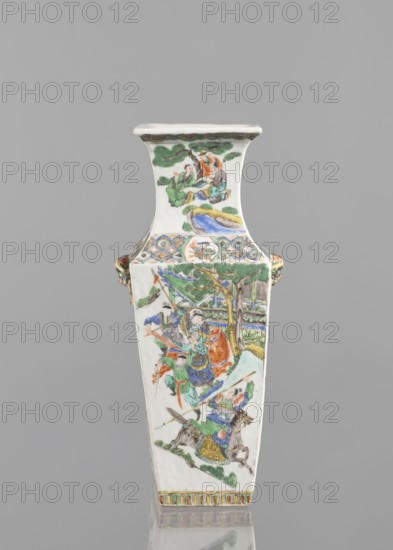 Vase, Chinese, 18th century. Colored porcelain vessel with figurative genre and battle scenes. Height 31.2 cm; width 11.0 cm., A tall, rectangular ceramic vase with a flared rim and a narrow base stands against a plain gray background. The vase is predominantly white with painted scenes in green, blue, orange, yellow, and brown, showing stylized trees, rocks, and human figures wearing flowing robes. Decorative bands with repeating patterns in blue, green, orange, and yellow encircle the vase near the top and bottom. On one side, a group of figures is depicted among trees and a pavilion-like structure, with some figures holding long objects and others seated; colors there include green, blue, orange, and brown. The opposite upper panel shows a smaller scene of seated figures beneath tree branches in green and brown with accents of orange and blue. Small sculpted handles in green and yellow protrude from the sides, and the vase rests on a reflective surface that mirrors its base and some...