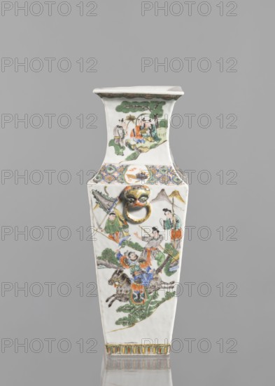 Vase, Chinese, 18th century, colored porcelain, figurative genre and battle scenes, vessel, height 31.0 cm, width 11.0 cm, A tall, tapered rectangular ceramic vase with a flared rim sits against a plain gray background; the vase is predominantly white with painted scenes in colors including green, orange, blue, yellow, black, and brown. The surface shows several painted figures in traditional dress engaged in activities among stylized trees and foliage rendered in green and brown, with one scene featuring a mounted figure on a gray horse wearing colorful garments in blue and orange. Near the upper section there is a decorative band with circular motifs in blue, yellow, and green, and a small sculpted face with a gold-colored ring projecting from the front. The rim has a thin decorative border in muted green and brown, and the base edge is accented with a repeating vertical pattern in yellow, green, and brown. The overall finish is glossy porcelain.
