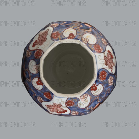 Vase with cover; creator, Japanese ceramics, Imari style; subject: flowers, tree, bamboos, peonies, karashishi; 18th century Edo period, 1603–1868, Japan; vessel; height 25.5 cm, diameter 16 cm., A top-down view of a ceramic vessel with an octagonal rim and a deep interior, showing a glossy inner cavity in muted grayish-green and an exterior decorated with a swirling pattern. The exterior features a background of deep blue with areas of white cloud-like panels containing floral and butterfly motifs in reddish-brown, along with smaller flower shapes in red and accents of gold. The vessel rim appears off-white with slight speckling, and the overall color palette includes blue, white, red, reddish-brown, gold, off-white, and grayish-green.