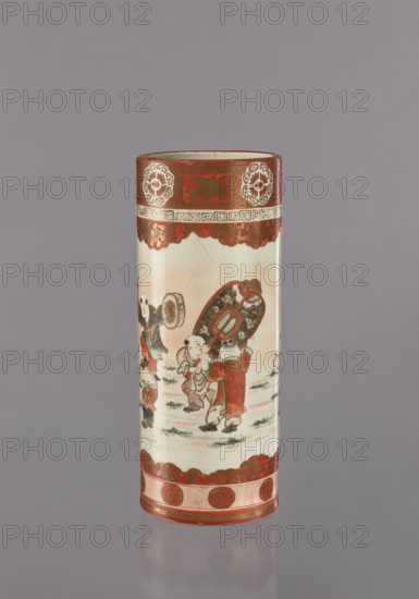 Vase, Kutani; cylindrical ceramic vessel, height 30 cm, diameter 12 cm; 1868–1912, Japan. Decoration: figurative scenes of one hundred sons/boys and plant ornaments. Materials/technique: ceramics., A cylindrical ceramic object stands upright against a plain gray background, decorated with painted scenes and bands of ornament. The upper rim is bordered by a wide red band featuring circular floral medallions and a patterned strip in lighter tones, followed by a scalloped red decorative edge. The central body shows a painted scene of children or small figures wearing traditional clothing in colors including red, green, brown, black, and cream, with one figure carrying an ornate oval object with detailed interior patterns. The lower portion has another scalloped red decorative band and a base band with circular red motifs on a textured lighter background. The surface of the object shows a crackled glaze in pale cream and off-white, and the overall palette includes red, cream, green, brown,...
