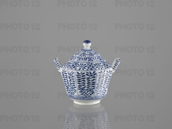 Sugar bowl with lid; maker, ceramics; sugar bowl; lid; Chinese; 20th century; China; vessel; height 12 cm., A ceramic covered vessel with a rounded lid and two small loop handles sits centered on a reflective surface; the piece is white with intricate blue painted floral and geometric patterns covering the body and lid, including stylized leaves and flowers and banded decorative motifs, and the reflection of the vessel appears faintly below it against a uniform gray background.