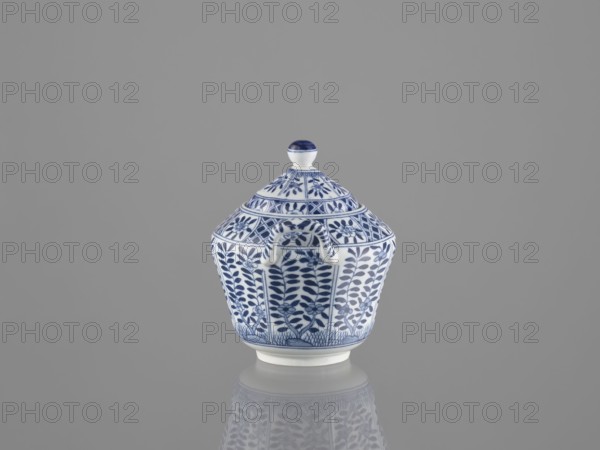Sugar bowl with lid, ceramics, sugar bowl, Chinese art, Chinese culture, lid, 20th century, China, vessel, height 12 cm, A small lidded ceramic container sits centered on a reflective surface against a plain gray background; the container is white with detailed blue floral and geometric patterns covering its body and lid, and it has a rounded finial on top with blue accents and a small curved handle on the side, with the blue-and-white motif mirrored faintly in the reflection below.