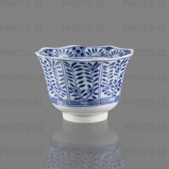 Bowl, Chinese, ceramics, 20th century, China, vessel; height 5.3 cm, diameter 7.8 cm, A small porcelain cup with a scalloped rim sits against a neutral gray background, decorated with a repeating blue floral and leafy pattern on a white ground, the blue designs appearing darker in some areas and lighter in others; the cup has a slightly flared shape narrowing to a short foot, and a soft reflection of the cup is visible on the glossy surface below.