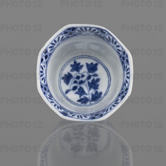 Bowl, Chinese, 20th century, China, ceramic vessel, height 5.3 cm, diameter 7.8 cm, A small ceramic bowl with an octagonal rim seen from above, predominantly white with blue painted floral motifs inside and a decorative blue border along the rim; the bowl sits on a smooth gray surface that produces a soft mirrored reflection beneath it, and visible colors include white, blue, and gray.
