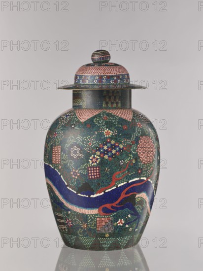 Vase with cover, Japanese, cloisonné enamel, Meiji 1868–1912, Man'en 1860–1861, ca. 1860–1870 Man'en 1–Meiji 3, Japan; vessel with cover depicting dragons and plant ornament; geometric-plant, geometric, shippo, kikko, and asanoha patterns; height 57.0 cm., A lidded ceramic jar sits against a neutral light gray background, showing a rounded body with a wide neck and a domed lid topped by a small knob; the surface is densely decorated with intricate patterns and motifs in green, dark blue, red, pink, white, gold, and black, including floral clusters, geometric tiles, and small repeating dot textures, with a sinuous dark blue and red ribbon-like form wrapping around the midsection and lighter pink and white accents along its edge, and the base reflected faintly on the glossy surface beneath.