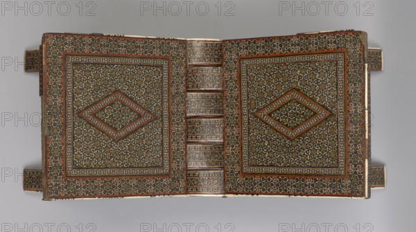 Quran lectern ra?la, 19th century, Iran Qajar dynasty, Persian; wood with geometric ornament; function: stand for the Quran; piece of furniture; unfolded: length 21.5 cm, width 41.4 cm; folded: length 41.5 cm, width 16.5 cm., An open decorative object with a symmetrical geometric pattern across both sides and a central spine, featuring a dense mosaic of small star-like motifs and diamond-shaped medallions; the design includes borders of repeating patterns and inset rectangular frames around the central diamond shapes, with visible tabs extending from the sides. The colors visible are brown, black, white, red, green, and gold, with mottled shading and fine linear details creating a textured, ornate appearance.