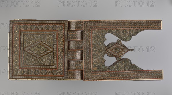 Quran lectern rahla, Islamic art, Persian art, Qajar dynasty 1785–1925, geometric ornament, stands, rahla, Quran, Persian culture, 19th century, Iran, piece of furniture; unfolded: length 21.5 cm, width 41.4 cm; folded: length 41.5 cm, width 16.5 cm., A rectangular carved object with intricate repeating geometric inlay patterns covering most surfaces, showing a central diamond motif framed by concentric decorative borders on the left panel and a matching patterned right panel with a cutout section and a raised diamond element; the design uses a palette of brown, dark green, black, cream, gold, and red tones, with some worn areas and slight variations in color intensity, set against a neutral light gray background.
