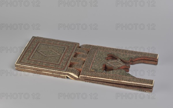 Quran lectern rahla, Islamic art, Persian art, Qajar dynasty 1785–1925, geometric ornament, stands, rahla, Quran, Persian culture, 19th century, Iran, piece of furniture; unfolded: length 21.5 cm, width 41.4 cm; folded: length 41.5 cm, width 16.5 cm, A flat decorative object with intricate patterned surfaces lies open on a light gray background, showing a pair of rectangular panels connected by hinged, curved sections; the surfaces feature dense small floral and geometric motifs in shades of brown, dark green, red, and cream with narrow borders and repeated designs, and the object has carved wooden edges and layered sides where the brown wood and cream inlay are visible.