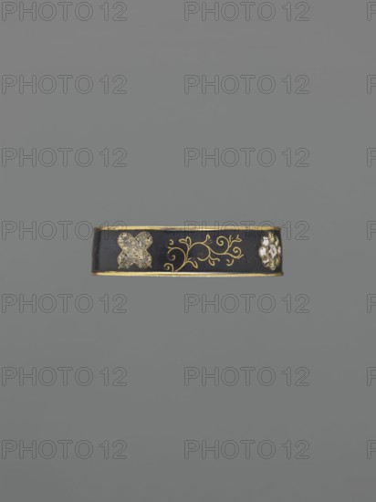Sword hilt ferrule kashira, Japanese, Edo period 1603–1868, 19th century. Katana hilt ferrule kashira with a flower rosette and stylized tendril motif. Materials: edged weapon hilt ferrule. Dimensions: height 1.0 cm, width 3.7 cm, depth 2.2 cm., A narrow decorative band centered against a plain gray background, the band is primarily black with thin gold edges and gold scrollwork in the middle, a textured pale four-lobed motif on one side, and a cluster of small pale rounded elements on the other side, with visible colors including black, gold, gray, and pale off-white.