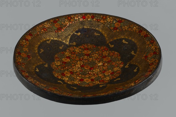 Plate, Islamic art, Persian, Qajar dynasty 1785–1925, floral ornament with flowers, 19th century, Iran, vessel, height 7.5 cm, diameter 42.0 cm, A shallow round tray with a dark base color decorated with intricate floral patterns in gold, red, orange, and green, featuring a central clustered floral medallion surrounded by scalloped dark sections edged with ornate gold filigree, and a rim adorned with repeating floral motifs in gold, red, and orange.