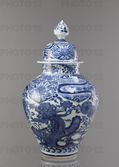 Vase with cover, unknown ceramist, Japanese, Edo period Genroku–Kyoho, ca. 1690–1730, Arita porcelain, blue-and-white porcelain, height 58.0 cm, diameter 35.5 cm. Decoration: phoenixes hoo, hares/rabbits, peonies, chrysanthemums, lotuses — kachoga flowers-and-birds motif. One of four elements of a set., A lidded porcelain jar with a bulbous body and a pointed finial lid predominantly in white and blue, decorated all over with intricate blue floral and foliate motifs, scrolling patterns, and stylized ornamental panels, set against a neutral gray background.