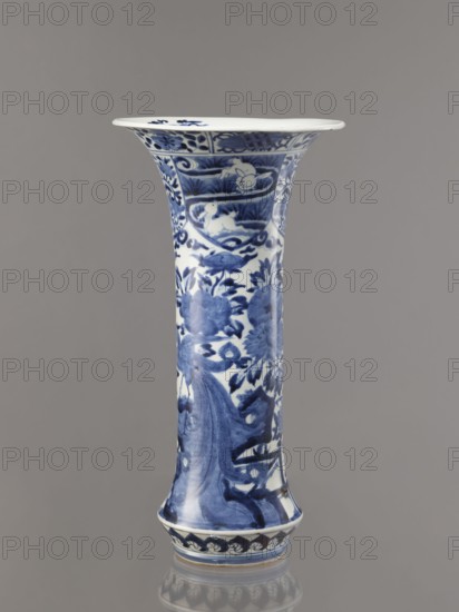 Vase, Japanese, Edo period 1603–1868, Genroku–Kyoho ca. 1690–1730, Arita; blue-and-white porcelain vessel, height 39.0 cm, diameter 20.3 cm; decorated with hares/rabbits, peonies, lotuses, phoenix hoo, kacho flowers-and-birds iconography. One of four elements of a set., A tall flared ceramic vase with blue painted floral and decorative motifs on a white ground, showing a group of stylized flowers and leaves and a few curved decorative bands, standing against a plain gray background.