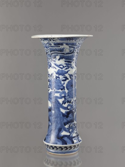 Vase, Japanese, Edo period Genroku–Kyoho, ca. 1690–1730, Arita; blue-and-white porcelain vessel decorated with phoenixes, hares/rabbits, peonies, chrysanthemums, lotuses—kacho/kachôga flowers-and-birds iconography; one of four elements of a set; height 39.0 cm, diameter 20.3 cm., A tall flared vase with a white base color and blue painted decoration sits against a neutral gray background; the vase has a flaring rim and a slightly widened foot with a glossy surface, and its blue designs include floral motifs, scrolling foliage, and abstract wave-like patterns that cover the body and neck, with darker and lighter shades of blue creating contrast and depth, and small areas of white left unpainted within the decoration.