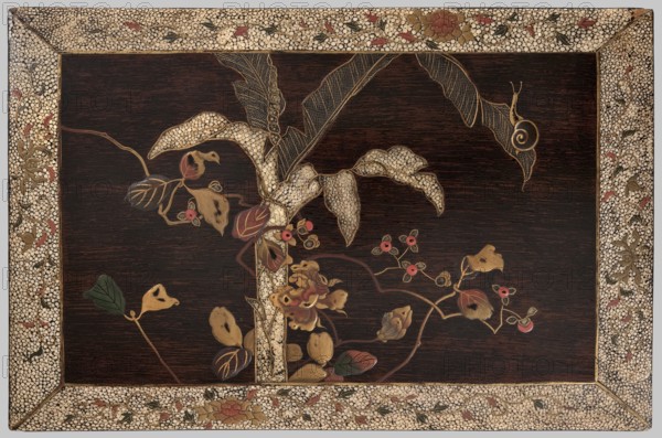Panel, Japanese art, Japanese culture, snails, leaves, peonies, plant motifs, banana trees, Meiji 1868–1912, Edo 1603–1868, inscription in Japanese on the reverse, 19th century, Japan, facing plate, height 28.5 cm, width 19.0 cm, A rectangular wooden panel with a dark brown background framed by an ornate border patterned with small pale beige pebble-like shapes and floral motifs in red, green, and gold, featuring a central decorative composition of stylized plant forms including large textured leaves rendered in pale beige and gold, several smaller leaves in shades of green and reddish-brown, curling vines in brown, clusters of small round berry-like shapes in pinkish-red, and a central multi-petaled flower in gold and reddish tones, with a small snail-like spiral motif on one leaf.