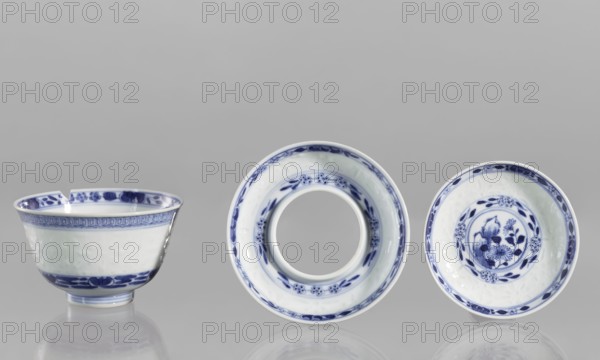 Bowl on a base with a lid; ceramics; rice-pattern geometric and plant ornament; rice porcelain; Chinese; Qing 1644–1911, late 18th century; floral arrangement in a circle at the bottom; signed; vessel; height 10 cm;, A neutral gray background with a reflective surface shows a group of three white ceramic vessels with blue painted decoration arranged in a row; on the left is a bowl with a slightly flared rim and blue floral and banded motifs along the rim and base, the rim has a small chip, in the center is a ring-shaped piece with a wide circular opening and blue floral bands around its inner and outer edges, and on the right is a shallow dish with a central floral motif surrounded by circular blue borders and leafy designs. The visible colors are white, blue, and gray.