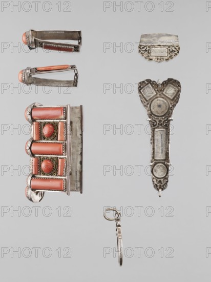 Braid ornament, braid ornament jewelry, artistic crafts; braid ornament, braids, women's ornament; 19th–20th century, Mongolia; jewelry; height 3.0 cm, width 7.8 cm, A collection of small metal objects arranged on a pale gray background, including a decorative rectangular piece with cylindrical coral-colored elements and oval coral cabochons set in ornate silver frames, a pair of hinge-like metal clips each with a coral-colored rounded end and silver filigree, an elongated ornate silver pendant with circular and heart-shaped motifs and decorative openwork, a small curved silver plate with scalloped edge and filigree details, and a thin silver ring attached to a narrow metal band; visible colors include silver, coral, gray, and a hint of gold in the filigree.
