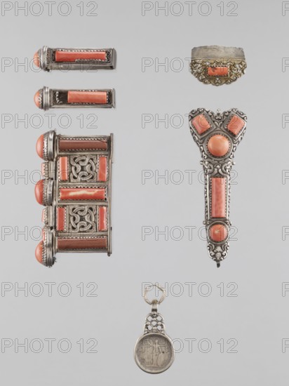 Braid ornament, braid ornament jewelry, Mongolia, 19th–20th century; women's ornament; materials: braid; height 3.0 cm, width 7.8 cm., A vertical arrangement of decorative metal objects on a light gray background, including a long ornate pendant with filigree details and coral-colored stones in rectangular and round shapes displaying silver metalwork, a matching triangular piece with similar coral-colored round and square stones and intricate silver filigree, a larger rectangular decorative box-like piece with coral-colored insets and lattice metal panels, a pair of small rectangular metal bars each set with coral-colored rectangular insets and rounded coral ends, a small ornate metal cap with a central coral-colored inset and scalloped filigree edge, and a round metal medallion pendant with a textured surface and a linked ring; visible colors include silver-gray metal tones, coral-pink stones, and the pale gray background.