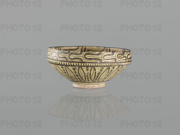 Bowl, 10th century Iran Nishapur, Persian Islamic ceramic vessel decorated with images of birds and palmettes, weight 1.11 kg, height 12.1 cm, diameter 26.0 cm, A shallow ceramic bowl with decorative patterns sits against a plain gray background, showing colors of beige, cream, black, brown, and a hint of reddish clay at its base; the bowl has a rounded shape with a slightly flared rim and a small foot, the exterior decorated with a band of repeating curved motifs near the rim and vertical leaflike or petal-shaped designs on the lower body, all rendered in dark lines on a light ground, and a soft reflection of the bowl appears beneath it on the surface.
