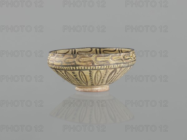 Bowl, 10th century, Nishapur, Iran; Persian Islamic ceramic vessel decorated with images of birds and palmettes; weight 1.11 kg, height 12.1 cm, diameter 26.0 cm., A shallow bowl with a rounded rim and a small foot, decorated with painted geometric and leaf-like patterns, shown against a plain gray background with a soft reflection below; visible colors include beige, black, brown, cream, and hints of ochre.