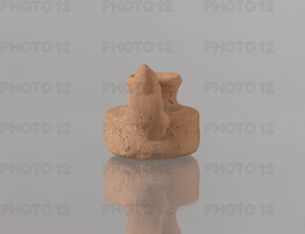 Oil lamp, Islamic art, Arabic culture, Fatimid dynasty 909–1171, Arabic pottery, Egyptian pottery, utilitarian oil lamp with traces of use, everyday life in the Middle East, 12th century, Egypt, height 3.4 cm, width 9.9 cm, depth 5.0 cm, A small, rounded clay object with a rough texture in brown and tan tones sits on a smooth, reflective surface, producing a muted reflection below; the background is a uniform light gray.