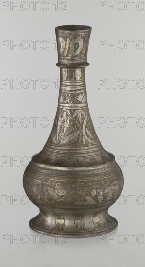 Bottle, gift, Islamic art, Arabic culture, geometric ornament, plant motifs, neck slender towards the top ending with a straight spout. Engraved patterns painted with golden-brown paint. Early 20th century, Middle East. Vessel. Height 21.6 cm, width 10.5 cm., A metallic vessel with a narrow flared neck, a bulbous midsection, and a footed base, rendered in shades of silver, gray, and muted gold, with engraved decorative patterns including leafy and geometric motifs covering much of its surface, a glossy reflective finish, and a neutral light gray background.