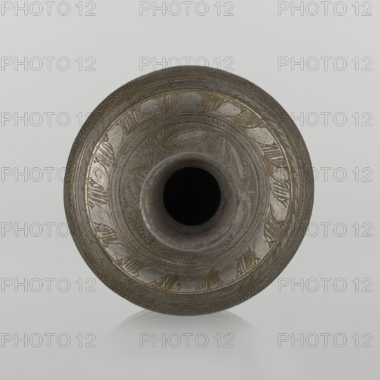 Bottle;, Early 20th century Middle East. Ceramic vessel, height 21.6 cm, width 10.5 cm. Neck slender toward the top ending with a straight spout. Engraved geometric and plant motifs, painted with golden-brown paint. Islamic art; Arabic., A round vessel viewed from above with a central narrow neck leading into a dark interior, the body showing etched decorative patterns and bands, the surface appearing metallic with tones of gray, dark gray, and muted gold, set against a light gray background and reflected faintly below.