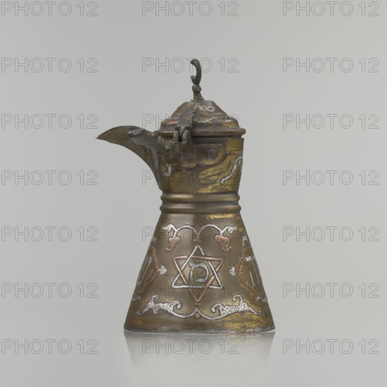 Coffee pot, ; Arabic and Jewish cultural influences; beverage vessel cezve. Decoration: Hebrew inscriptions inlaid in copper, Star of Solomon motif, arabesque patterns. Hinged lid with hinge halfway down the handle; lid topped with a crescent. Inscriptions deciphered: reads drinking; in the hexagonal star Gan Eden, garden; in the cartouche for celebration; under the handle, in the Seal of Solomon/Star of David Mim from the word water. Early 20th century, Palestine. Vessel: height 15.5 cm, width 15.5 cm, diameter 8.7 cm., A metal pitcher with a conical base and a hinged lid sits against a plain light gray background; the pitcher shows a worn metallic finish in shades of brass, bronze, and dark brown with areas of silver and copper inlay forming decorative curving motifs and a central six-pointed star design on the body; the spout extends from the upper portion with a sculpted hinge and a small curved finial atop the lid, and the surface exhibits patina and slight scratches with reflecti...