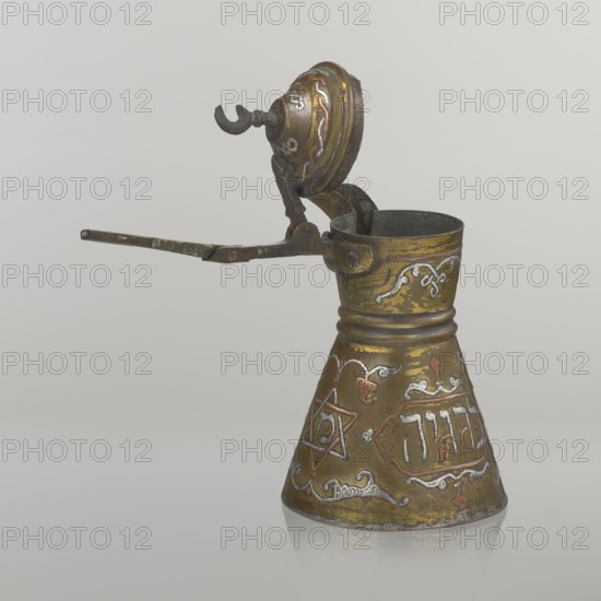 Coffee pot, gift; Arabic and Jewish cultural influences; beverage vessel cezve. Beginning of the 20th century, Palestine. Materials and decoration: copper with Hebrew inscriptions inlaid in copper, Star of Solomon motif, arabesque patterns. Hinged lid hinge halfway down the handle; lid topped with a crescent. Inscriptions deciphered: drinking; in the hexagonal star Gan Eden, garden; in the cartouche for celebration; under the handle, in the Seal of Solomon/Star of David Mim from the word water. Vessel dimensions: height 15.5 cm, width 15.5 cm, diameter 8.7 cm., A small metal vessel with a conical base and a narrower cylindrical neck, shown with its hinged lid open and a long narrow handle extending outward; the object has a worn metallic surface in shades of brassy gold and darker bronze with areas of patina and tarnish, and decorative raised patterns and accents in silvery and reddish tones, including a few ornamental scrolls and a six-pointed star motif; the interior and some hinge c...
