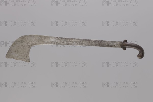 Sabre of the bark type, With a curved hilt and similar expanded engraving. Decorated with representations of animals: lions, a horse, a rhinoceros, a camel, elephants, a hare and a plant twig. 1st half 20th century. India /Nepal . Weapon. Height 69.0 cm, width 14.5 cm. Cultural context: Indian; materials and motifs include bark weapon, plant ornament, zoomorphic motifs lions, tigers, other animals., A long metal blade with a curved hooked tip and a rounded, curved dark handle; the blade shows engraved decorative patterns and a patina in shades of silver and gray, while the handle appears dark brown to black with worn lighter highlights; the background is a uniform pale gray.
