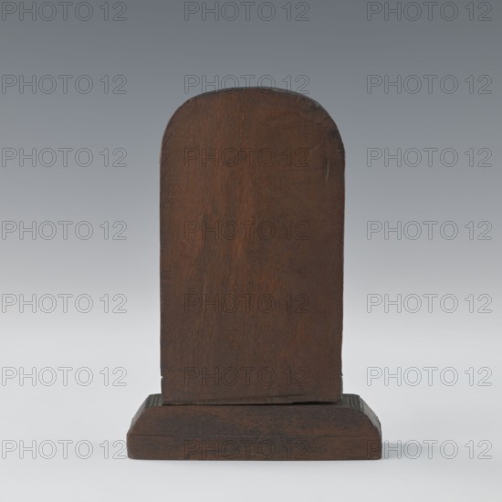 Hanuman, Indian, 1st half of the 20th century. Bas-relief, height 9.8 cm, width 8.8 cm. South Asian/Indian art; subject: Hanuman monkey servant of Rama and Sita related to Vaishnavism and the Ramayana; depicts armlets., A single upright wooden plaque with a rounded top mounted on a rectangular wooden base, both showing a rich brown wood grain with darker brown variations and subtle worn areas, set against a smooth gray gradient background with lighter gray near the bottom and darker gray toward the top.