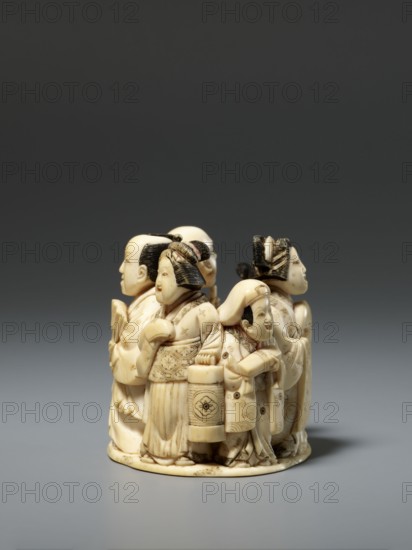 Okimono in the shape of a group of six singing people; late 19th century Meiji period, Japan. Carved figurines okimono depicting a courtesan with a small kamuro servant, a townswoman carrying a lantern, a wealthy merchant with a fan, a messenger with an oblong box, and a blind Buddhist monk with a shaved head leaning on a cane. Material: sculpture; style: Japanese Meiji; height 5.1 cm, width 5.2 cm, depth 4.5 cm., A small circular carved object in a pale ivory tone sits on a smooth gray surface against a dark gray background; the carving depicts a group of traditional figures arranged around the circle, each wearing detailed garments with incised patterns and hairstyles highlighted with darker brown shading, and one figure holds a cylindrical lantern-like object with carved ornamentation, while the base shows subtle age-darkened areas and the overall colors visible are ivory, dark brown, light gray, and dark gray.