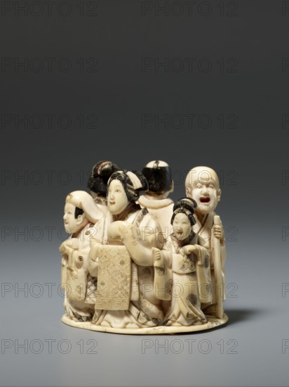 Okimono in the shape of a group of six singing people; late 19th century Meiji period, Japan; sculptural figurine okimono; height 5.1 cm, width 5.2 cm, depth 4.5 cm. The group of six figures depicts representatives of various urban environments of old Japan: a courtesan with a small kamuro servant, a townswoman carrying a lantern, a wealthy merchant with a fan, a messenger with an oblong box, and a blind Buddhist monk with a shaved head leaning on a cane. Japanese art; materials and, A group of small carved figures arranged on a round base, all carved from a pale ivory-colored material with darker brownish-black accents in the hair and carved details; the figures wear intricately carved garments with patterned textures and raised folds, showing a few layered robes and sashes; several figures have hair styled in traditional updos or shaved heads with dark inlaid hair, and their faces are smooth and expressive with subtle smiles or open mouths; one figure holds a staff, another appears t...