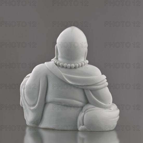 Budai Laughing Buddha, 19th century China, Fujian; Qing dynasty; material/technique: figurine; iconography: Budai Buddha of the Future, Maitreya, Milefo; dimensions: height 30.4 cm, width 21.6 cm; weight 3 kg., A smooth white ceramic figure viewed from the back showing a rounded head, a beaded necklace, draped robes with flowing folds, and a seated posture on a reflective surface against a plain gray background; visible colors include white and shades of gray.
