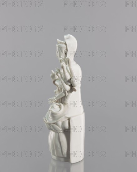 Guanyin on a lotus throne, Blanc de Chine porcelain, 18th century, China, Fujian; Chinese Buddhist goddess Guanyin; sculpture; height 27.0 cm, width 14.3 cm; inscriptions: none noted; subject: Guanyin iconography; material and technique: Blanc de Chine porcelain., A glossy white ceramic statue is shown against a smooth pale gray background, depicting a seated figure with multiple delicate arms and detailed hands, a serene facial profile, and a flowing robe that melds into a stylized base resembling a lotus; the surface shows subtle reflections and small imperfections, and the statue sits on a reflective surface that creates a soft mirrored shadow.